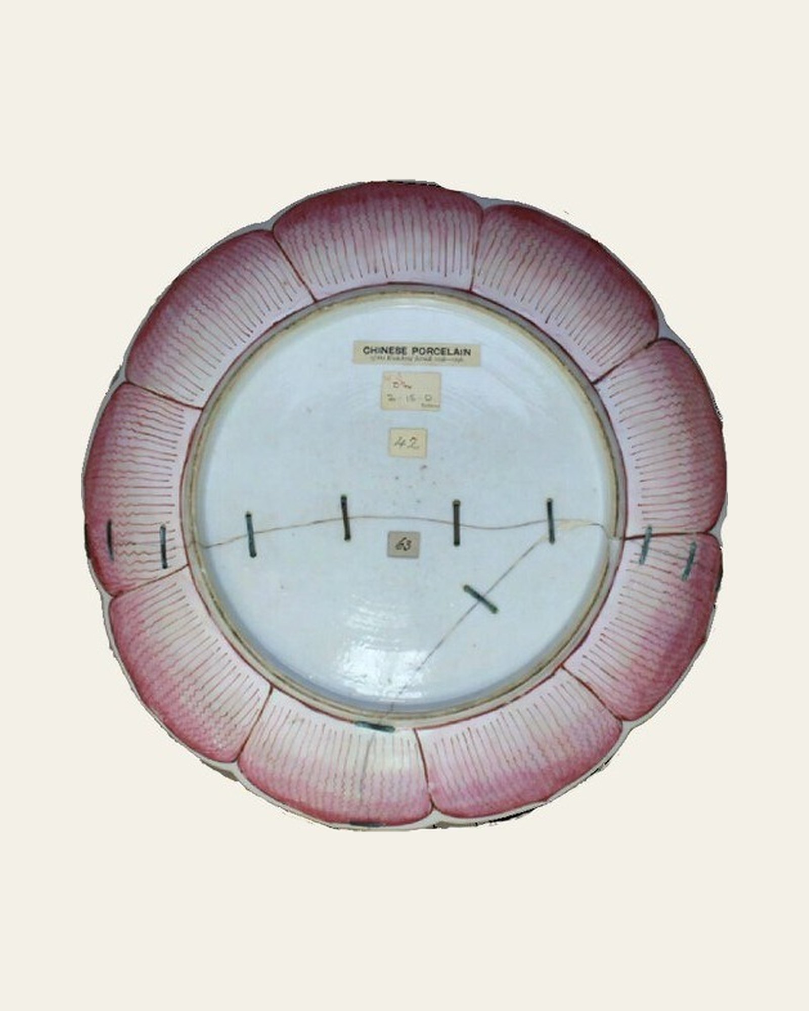 Reverse of the Qing dynasty famille rose porcelain dish before conservation, with earlier riveted repair.